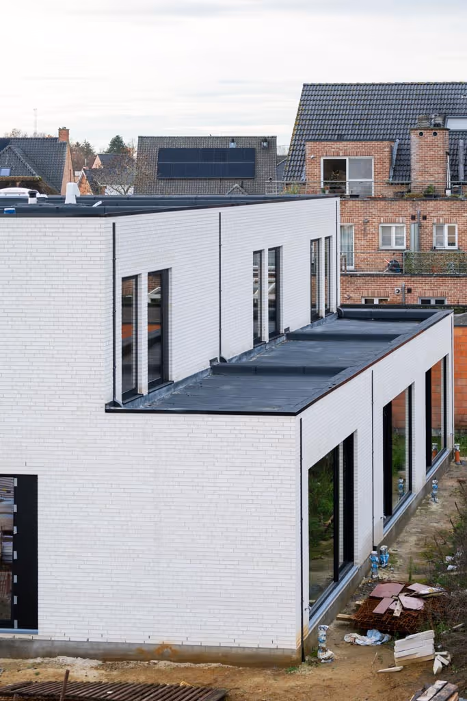 Foto van afgewerkte woningen met plat dak in nieuwe roofing, witte gevelsteen en zwart buitenschrijnwerk.