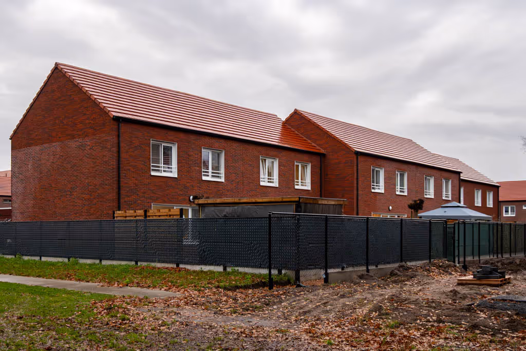 Gerenoveerde woningen met rode gevelsteen, rode dakpannen en witte ramen.
