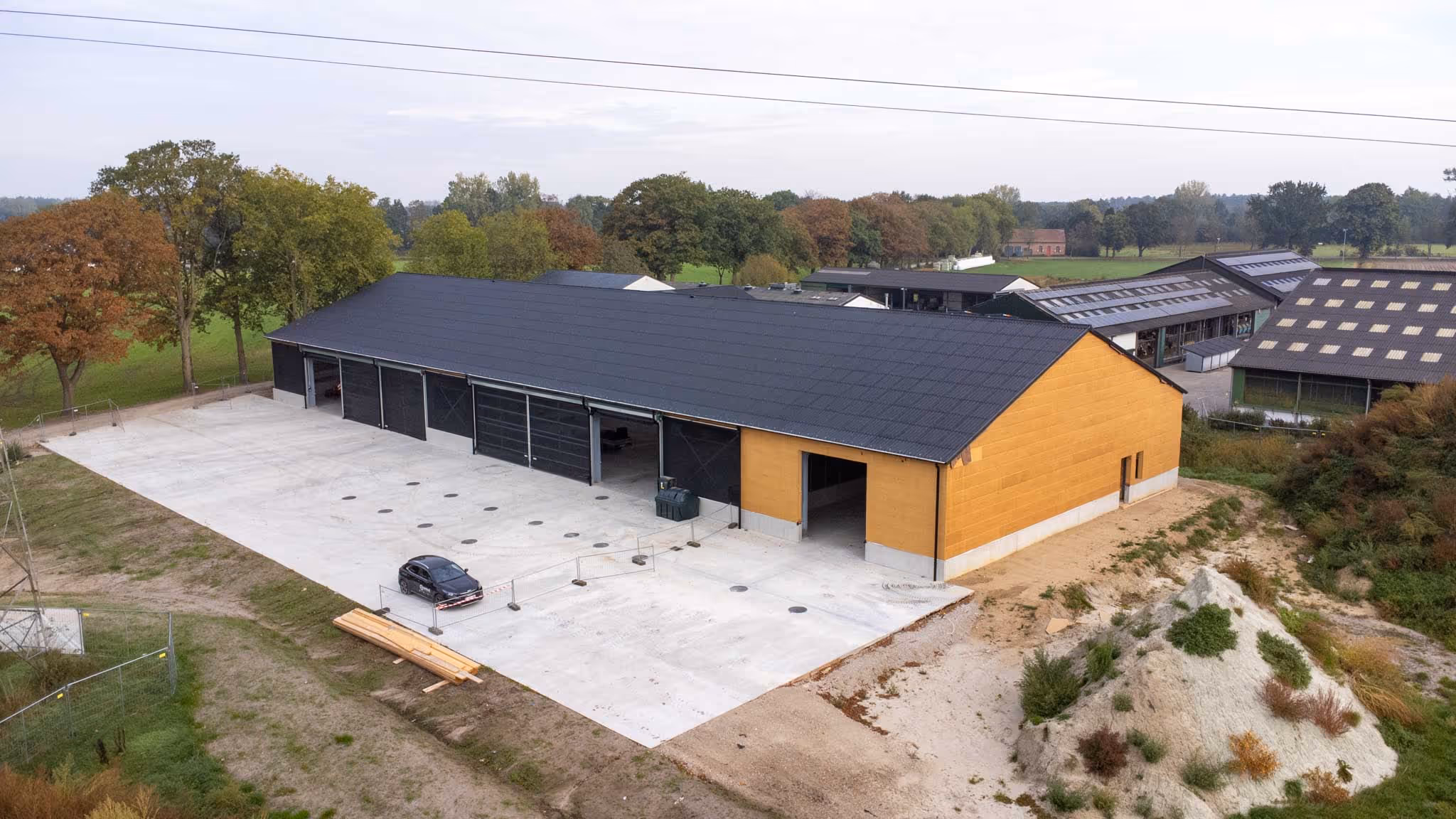 Nieuwbouwhal opgebouwd uit houtskelet, voorzien van zwarte golfplaten.