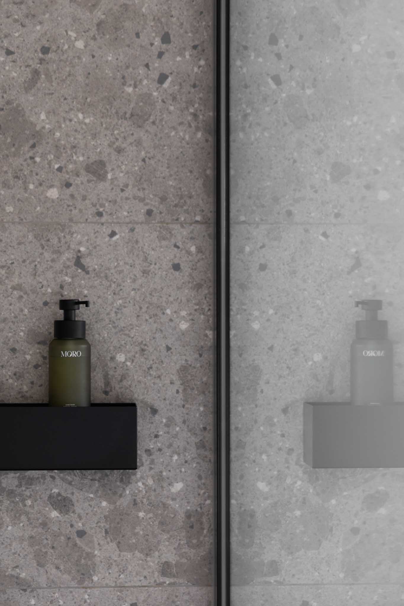 Moderne badkamer na renovatie met als detail de zwarte zeephouder en glazen wand.