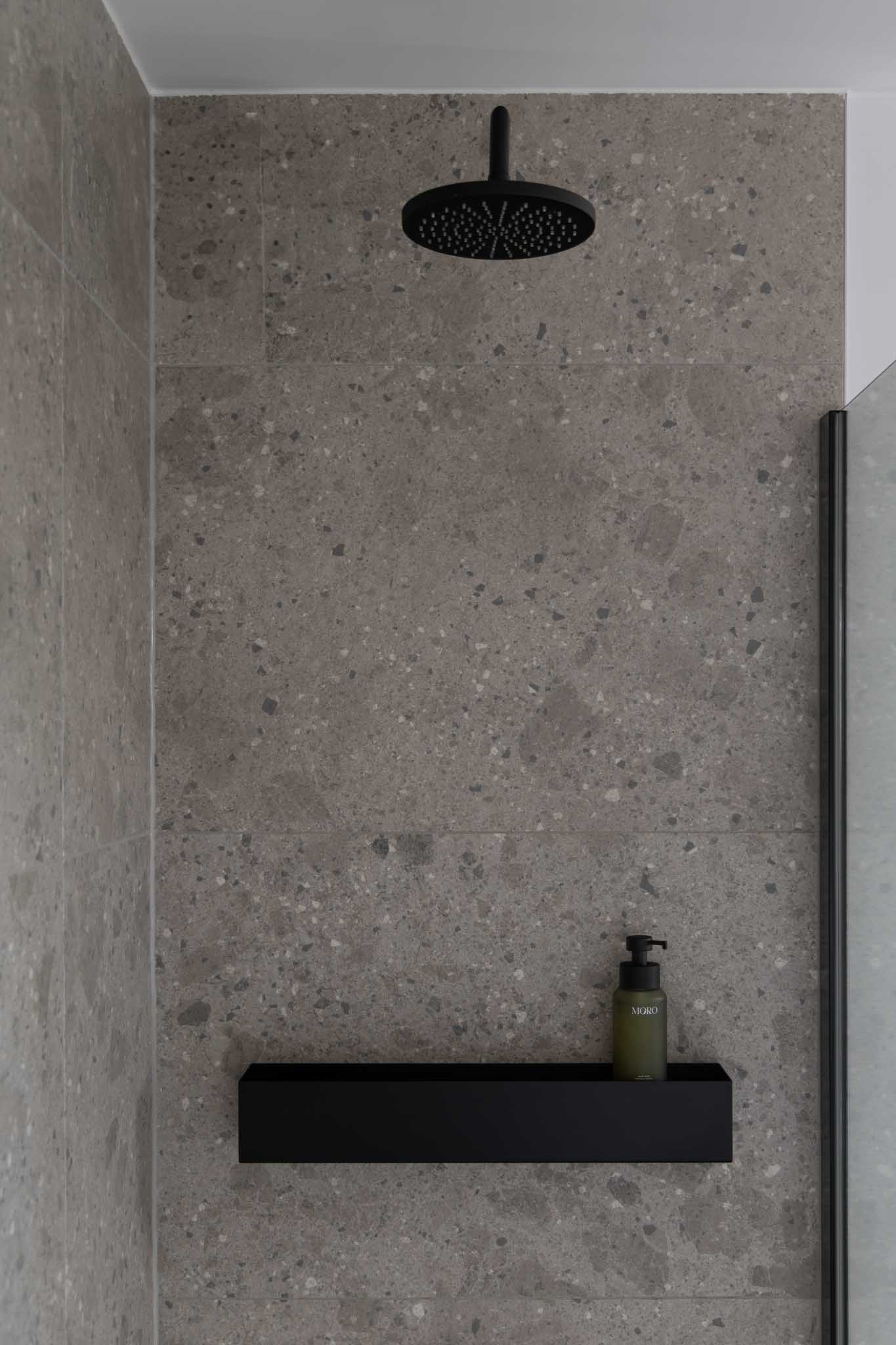 Moderne badkamer na renovatie met inloopdouche en zwarte details.