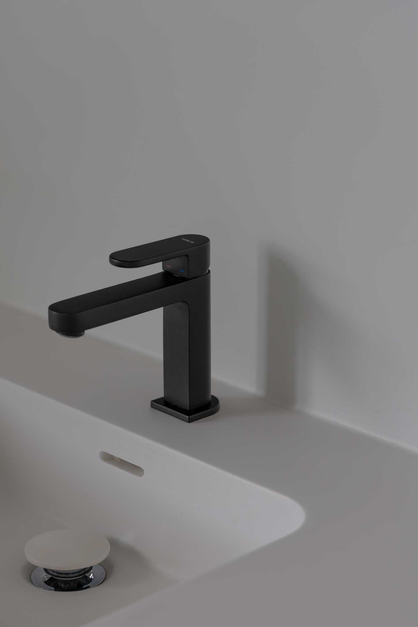 Moderne badkamer na renovatie met als detail de zwarte kraan boven de witte spoelbak.