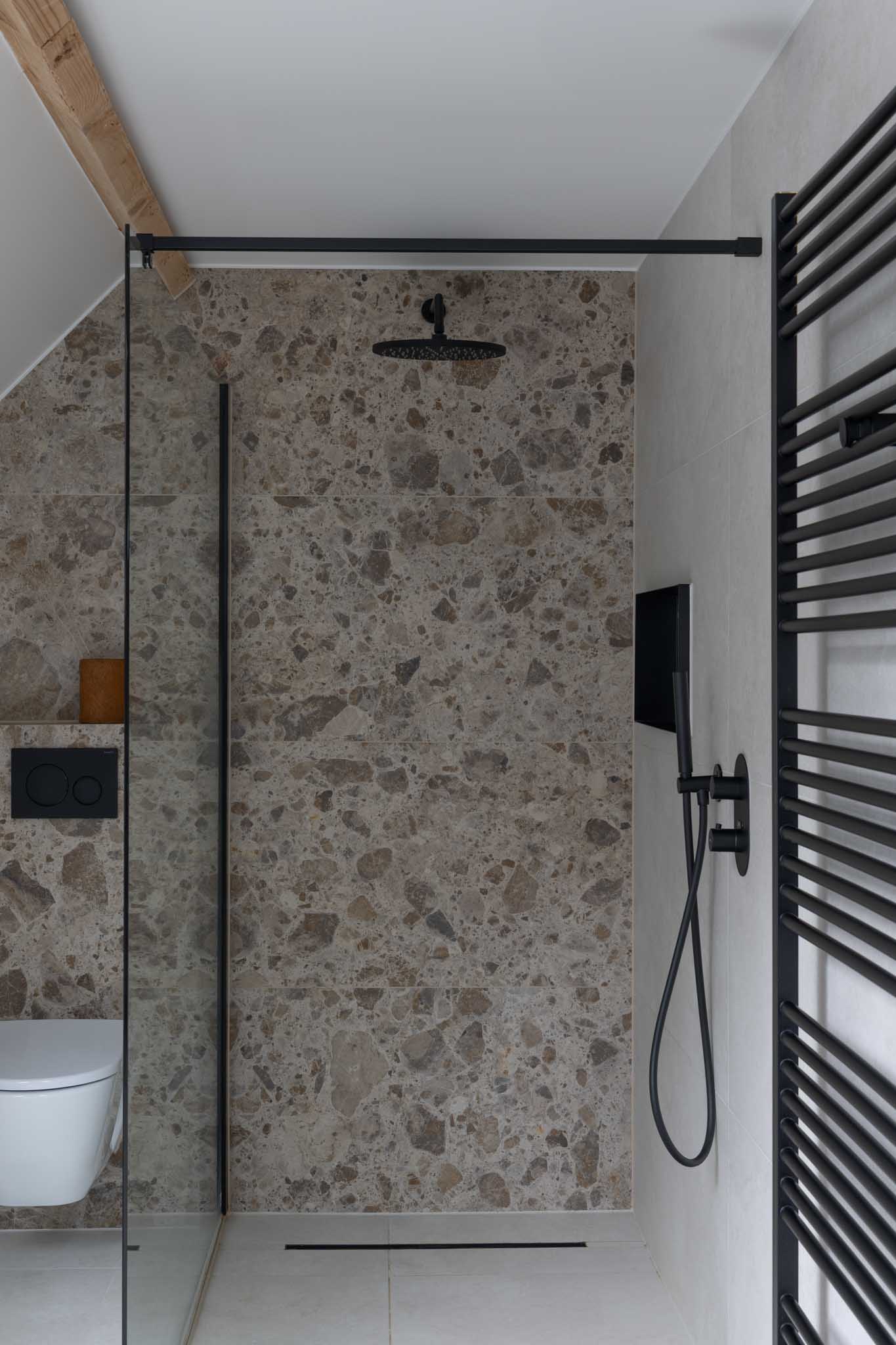 Moderne badkamerrenovatie met inloopdouche met zwarte details.