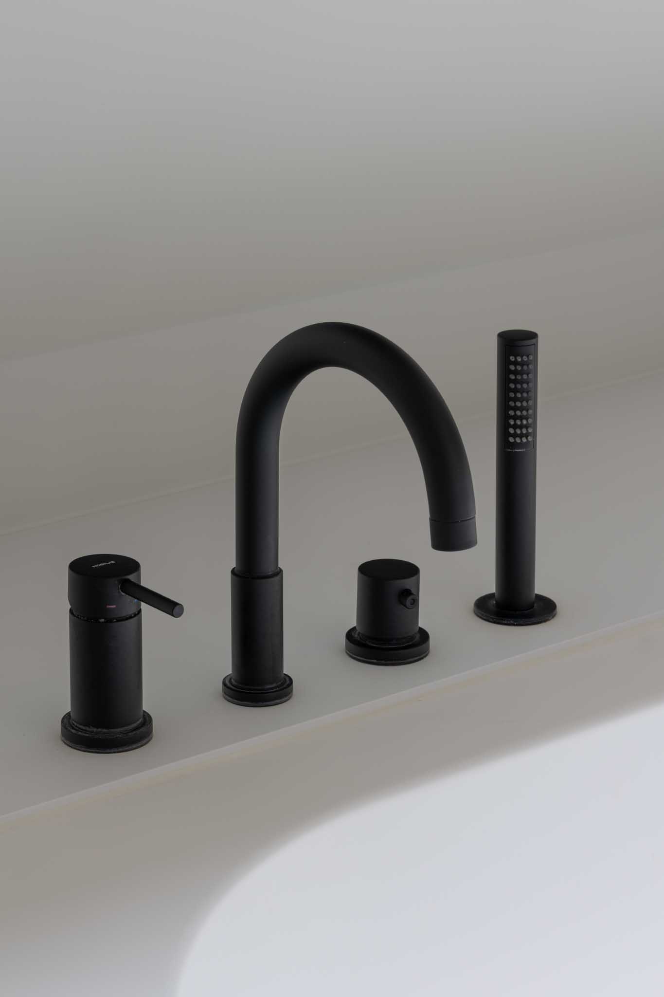 Moderne badkamerrenovatie met als detail de zwarte kranen op het bad.