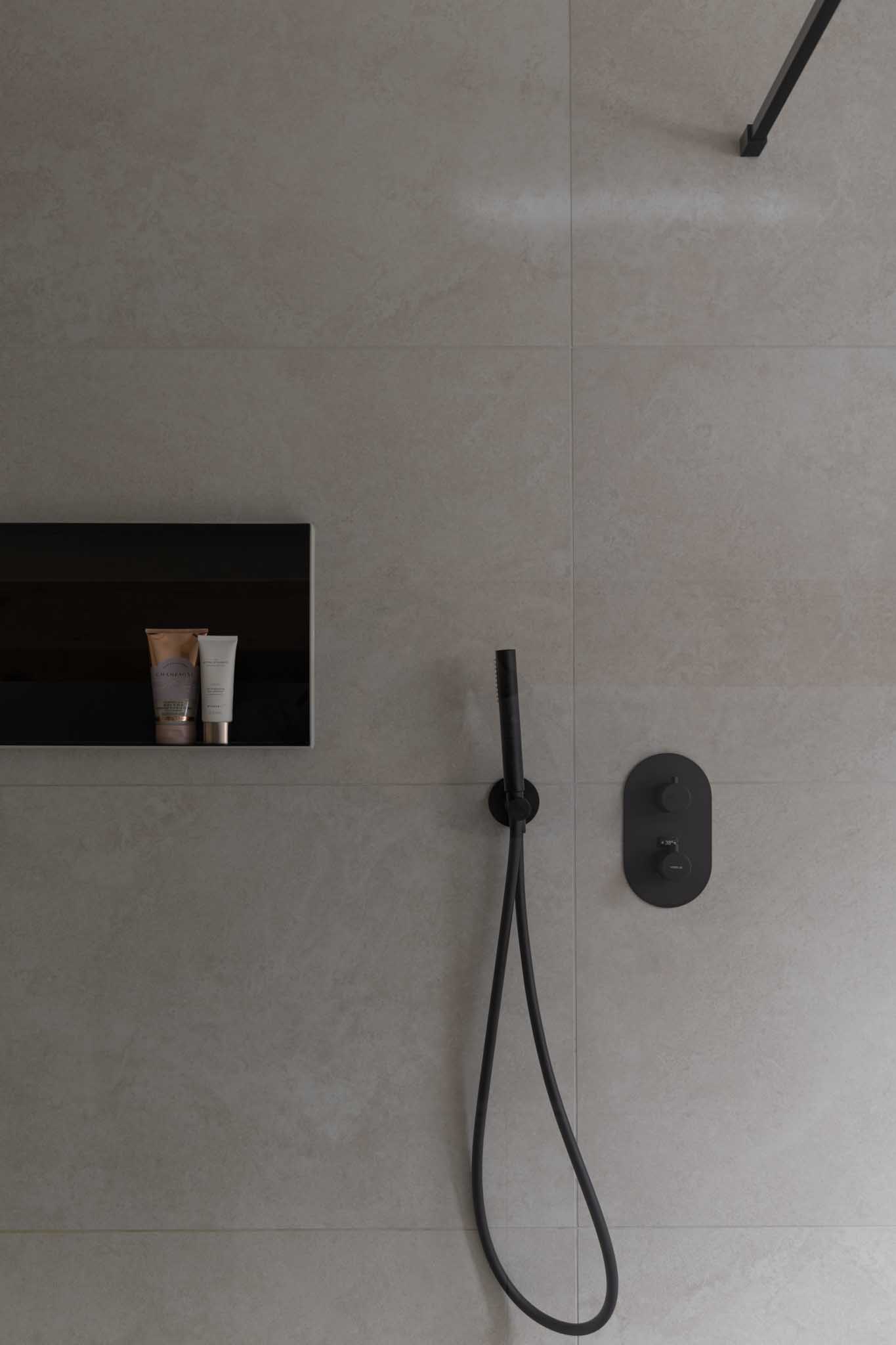 Moderne badkamerrenovatie met beige wandtegels in de inloopdouche en zwart kraanwerk.