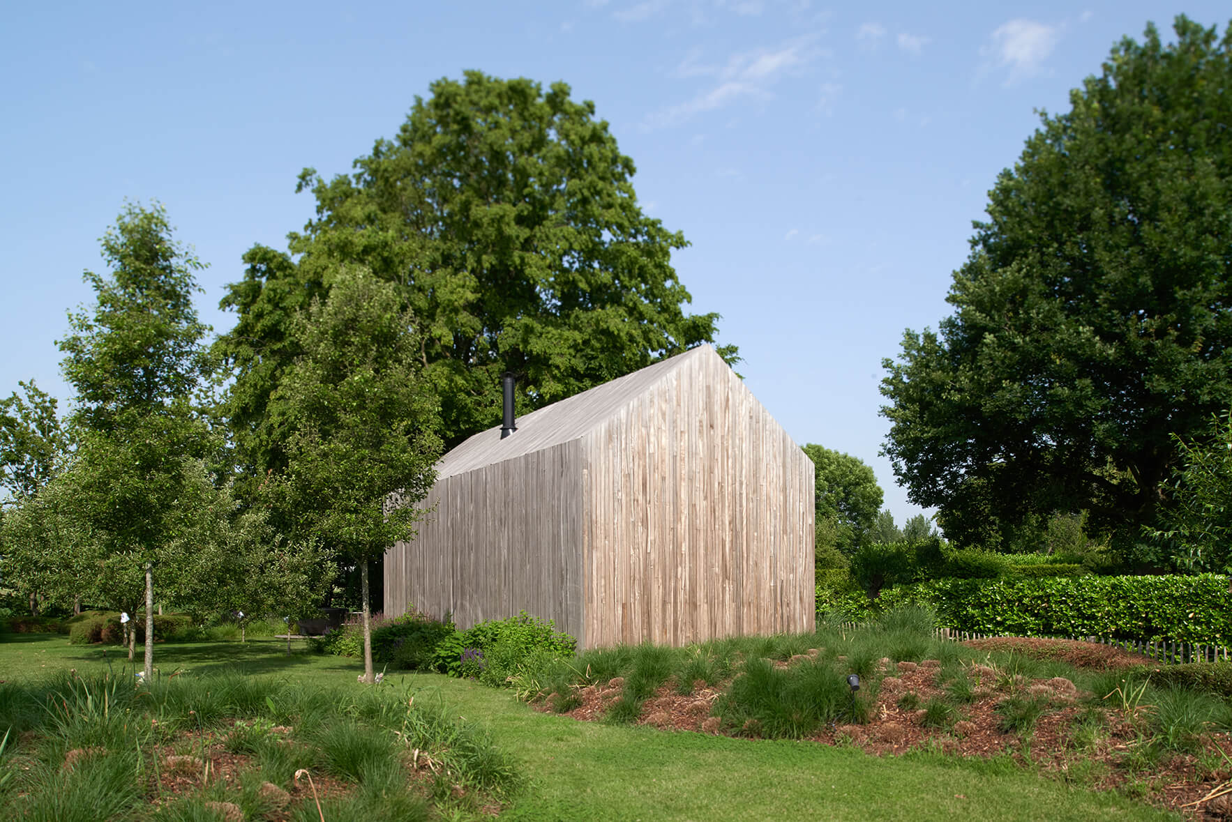 Houten tiny house als duurzaam vakantiehuis midden in het groen, omgeven door bomen en natuur.