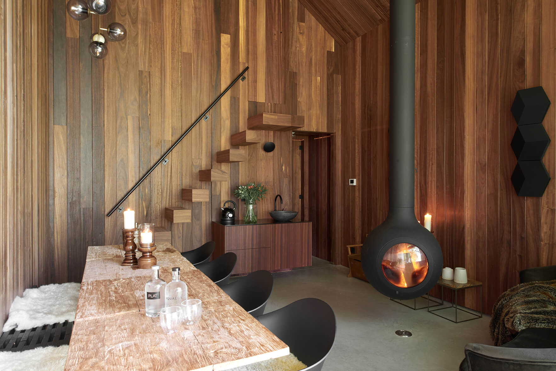 Interieur van tiny house uit houtskelet met tafel, stoelen, kachel en houten trap.