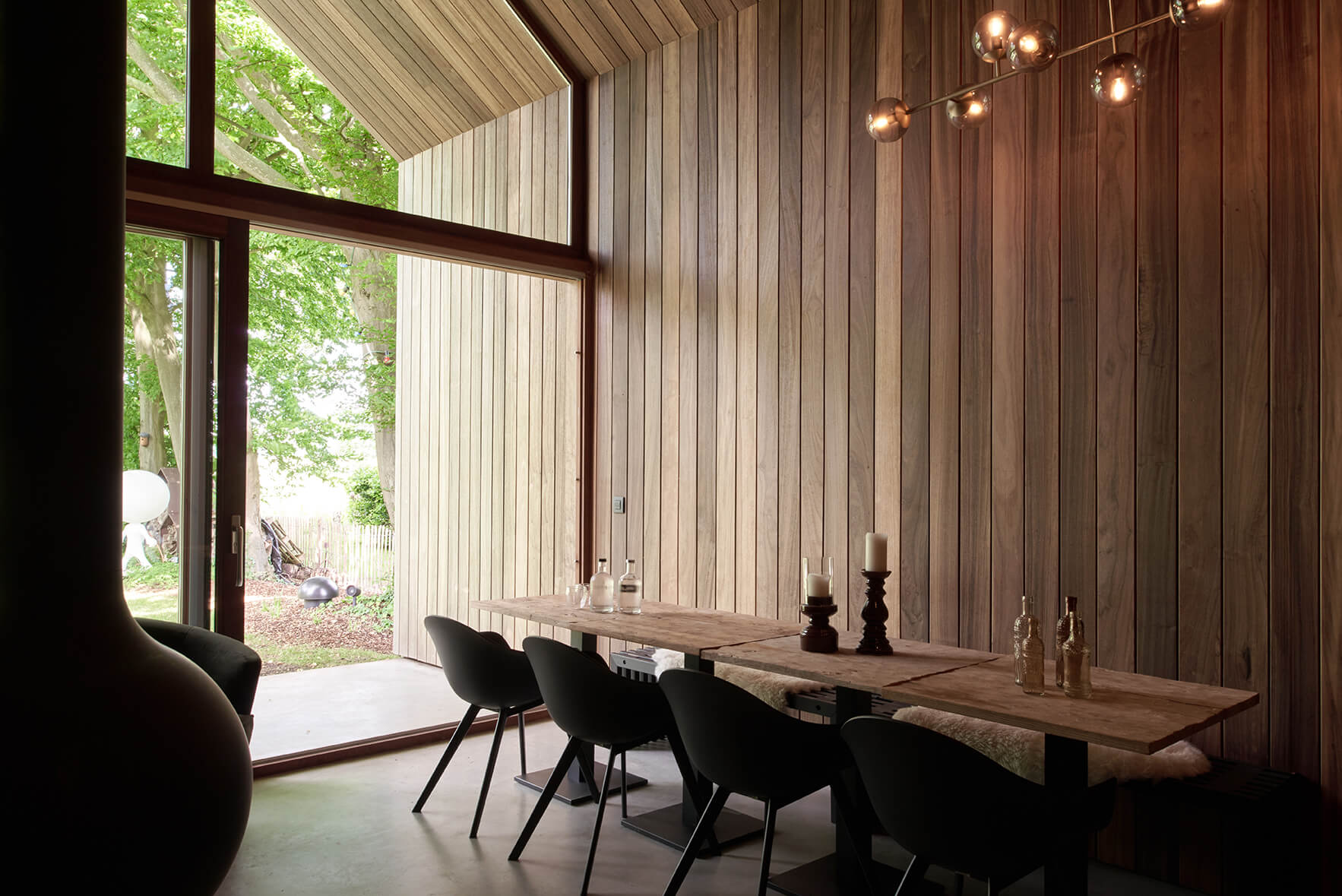 Interieur van tiny house uit houtskelet met eettafel, grote ramen voor veel licht en houten bekleding.
