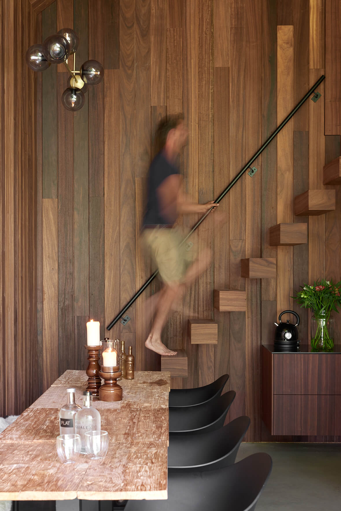 Bartel Van Riet die de trap oploopt in het houten tiny house, met de eettafel op de voorgrond.