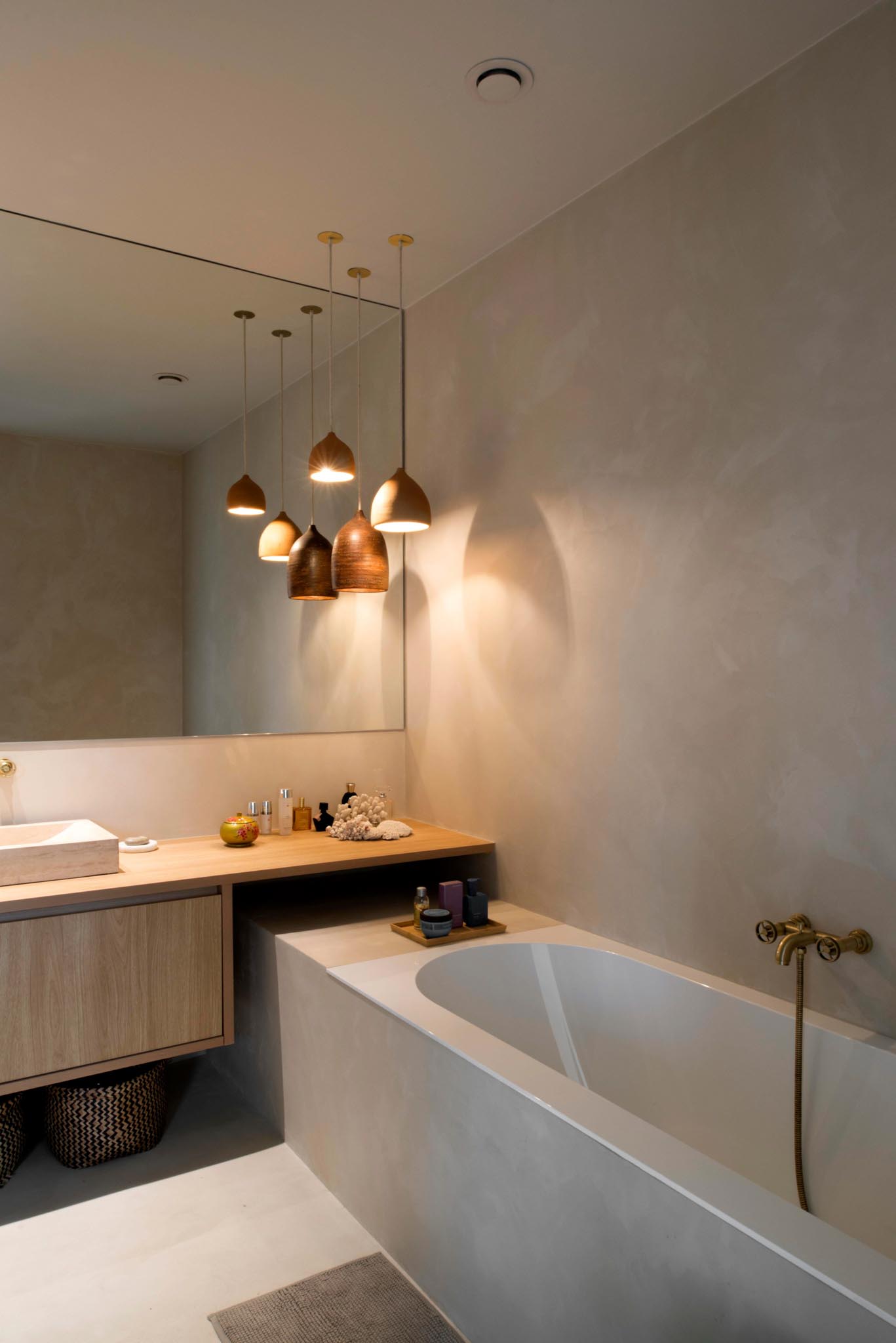 Moderne badkamerrenovatie met ingebouwd bad, houten meubel en grote spiegel.