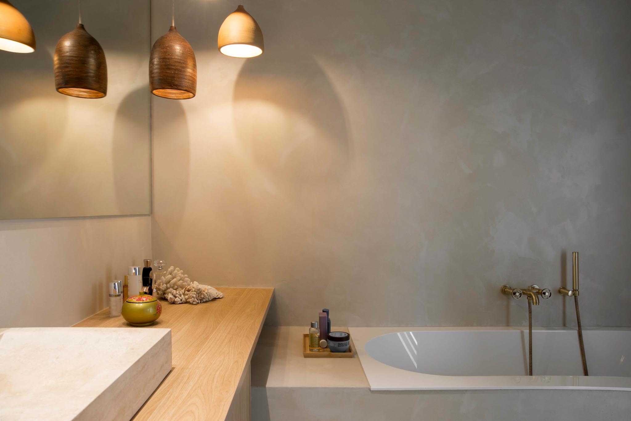 Moderne badkamerrenovatie met zachte kleuren, wit bad en houten werkblad.