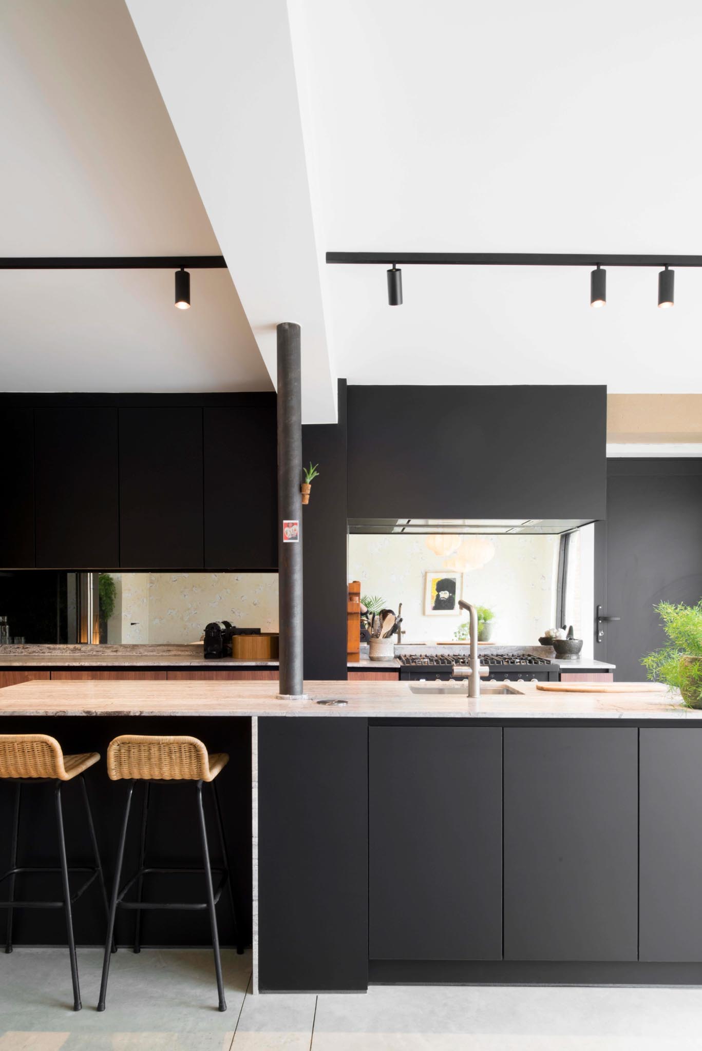 Keuken na totaalrenovatie met zwarte kasten, grijs werkblad en steunpaal.