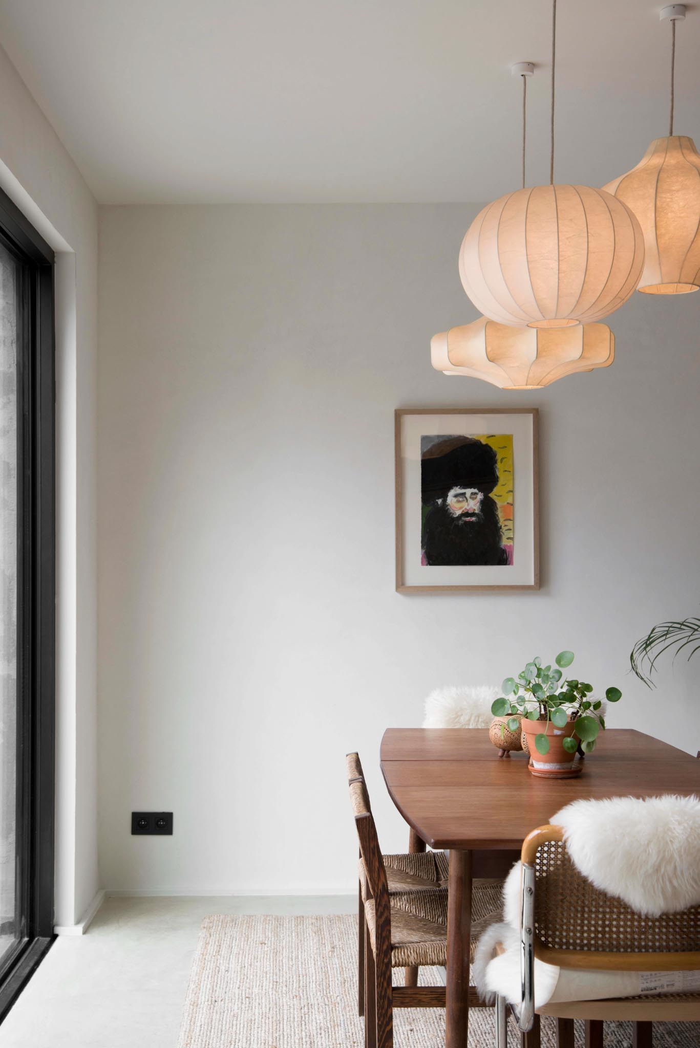 Woonruimte na totaalrenovatie met eettafel, lichte muren en wanddecoratie.