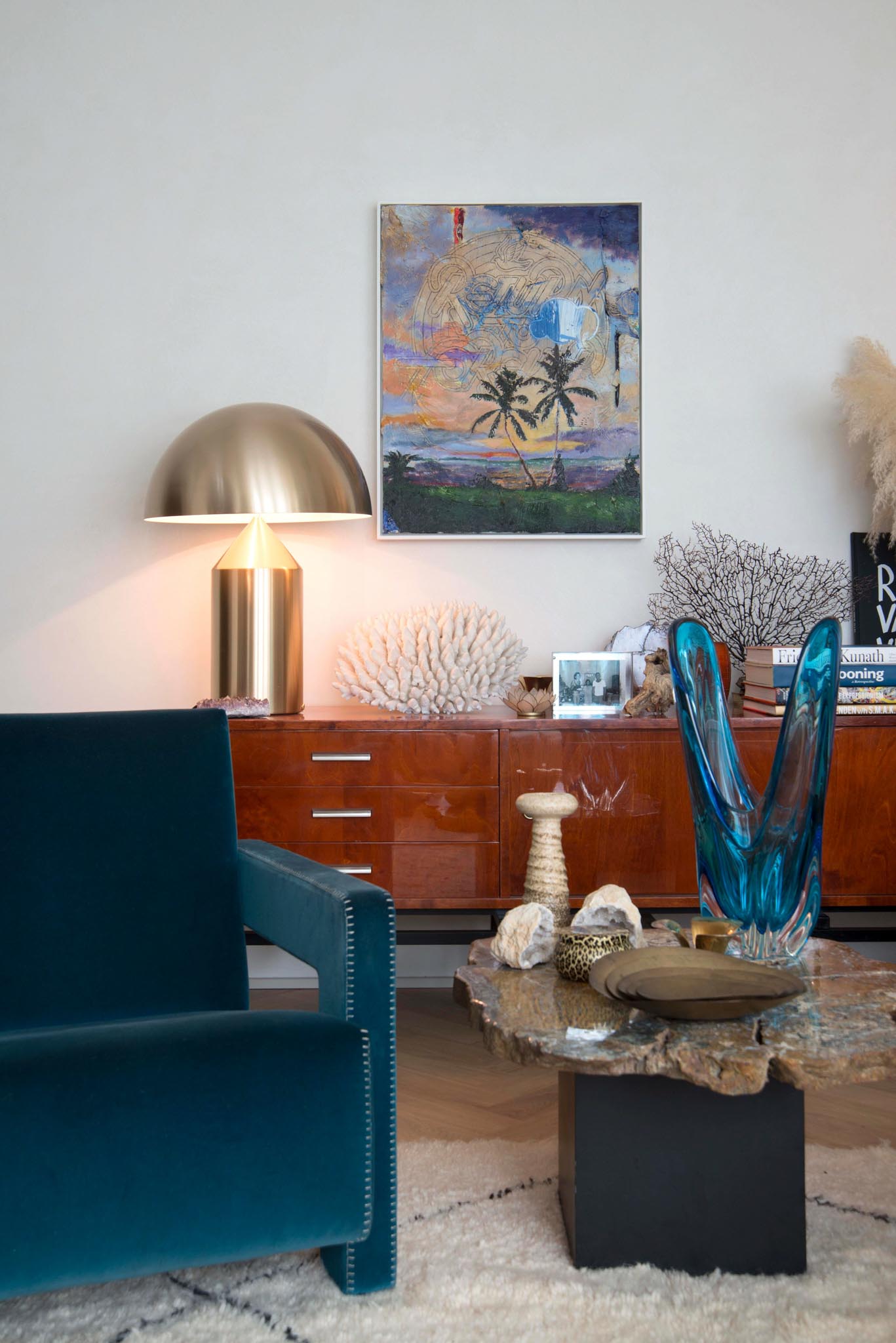 Leefruimte na totaalrenovatie met blauwe zetels, rode kasten, vloertapijt en decoratie.