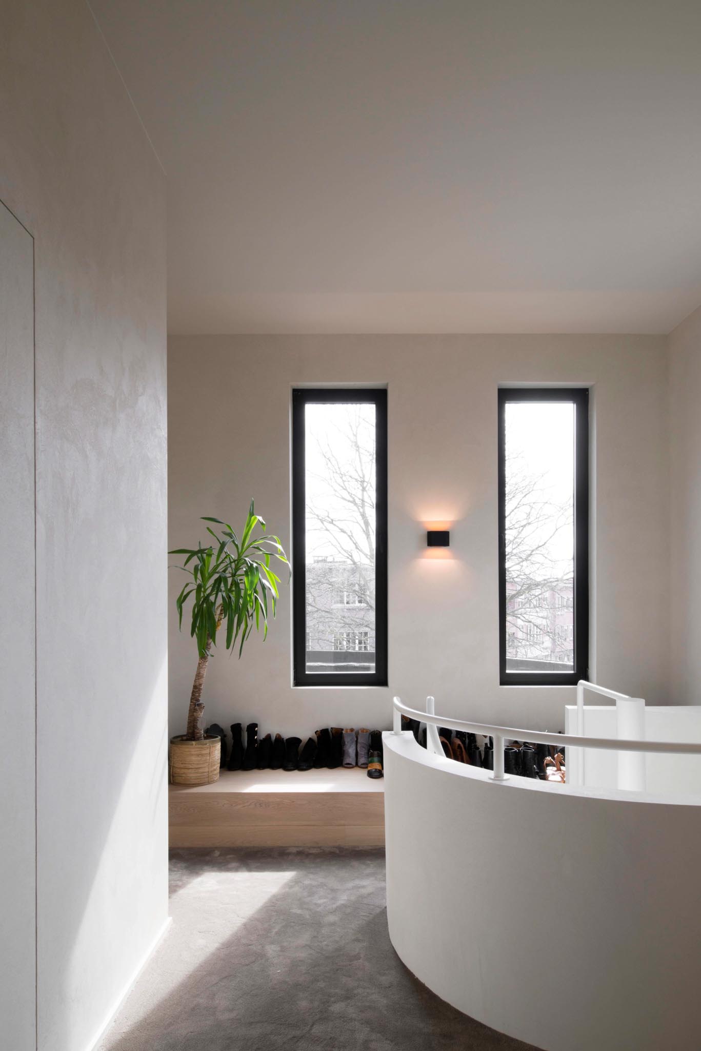 Lichtrijke nachthal na totaalrenovatie met ronde balustrade, zachte kleuren en antraciet ramen.