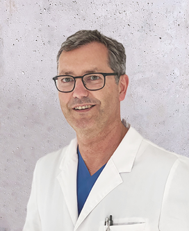 Mittelalter Mann mit Brille und weißen Arztkittel vor hellgrauer Wand.