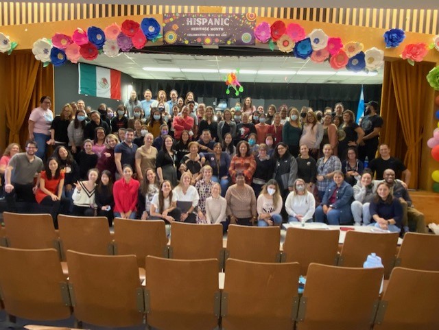 Large group of diverse people posing on a stage decorated with colorful paper