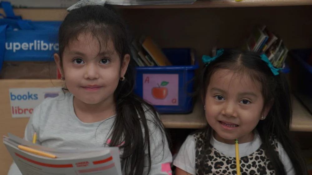Two young girls sitting in front of bookshelves,