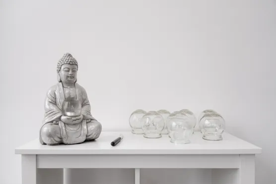 Ein Bild von einem Regal mit Schröpfgläsern und Buddha-Statue.