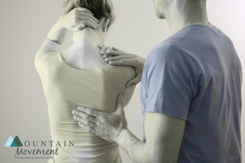 A chiropractor touching a womans back to find the points of pain