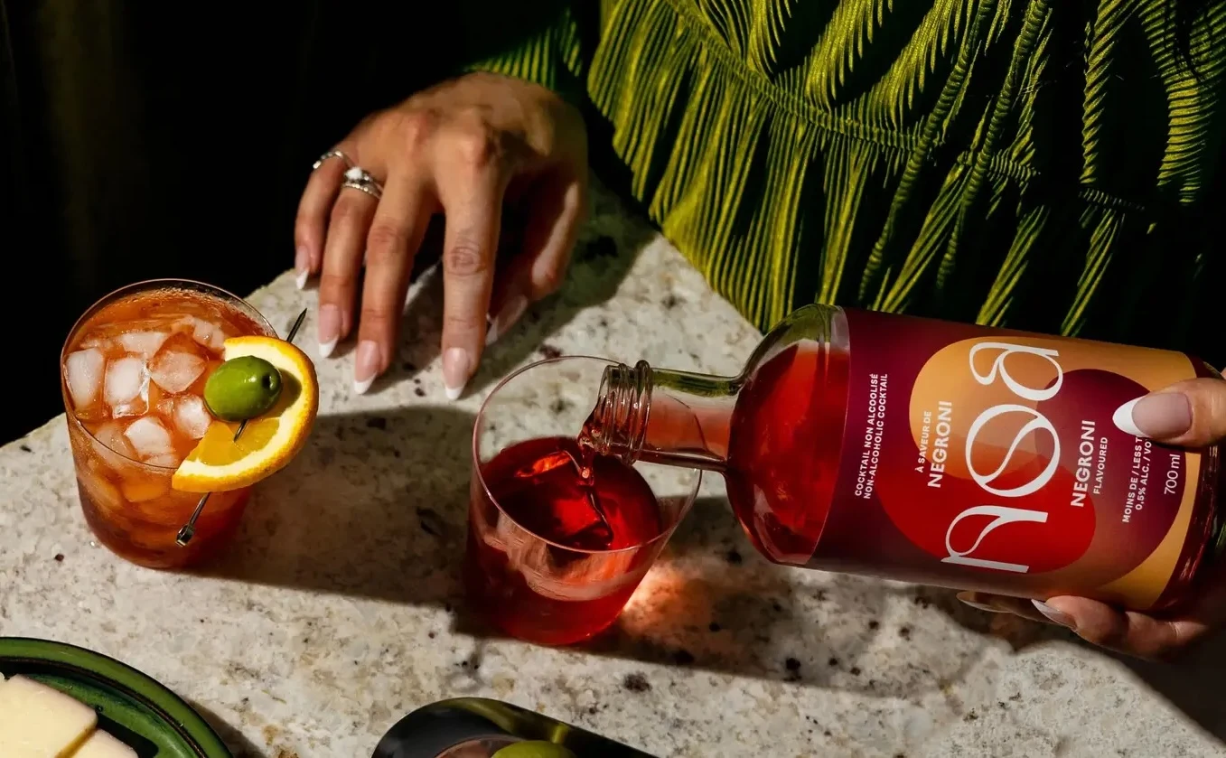 A woman bartender stirring her drink in a dim light bar