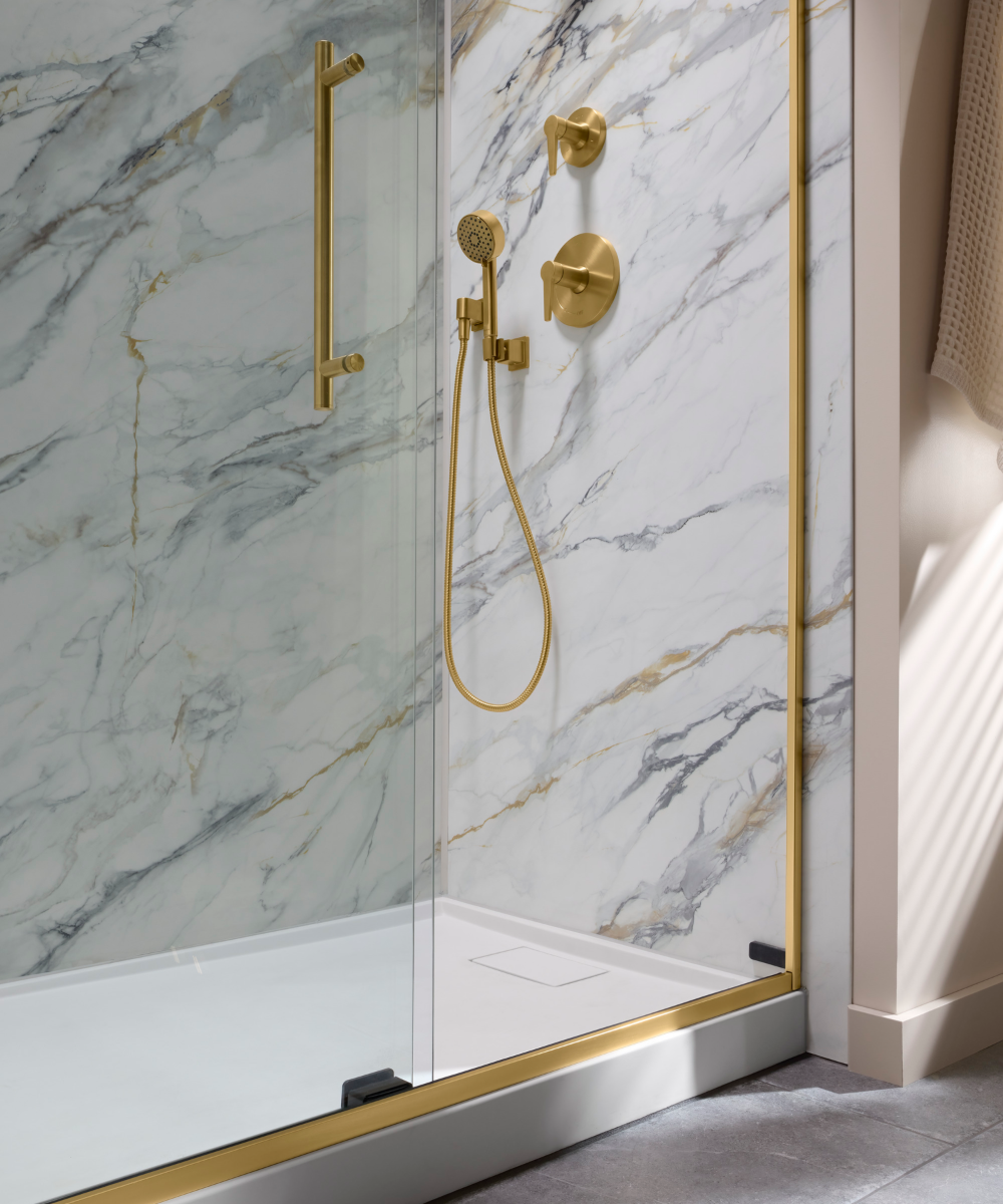 Beautifully remodeled Kohler shower with seamless glass doors and beautiful crushed stone walls.