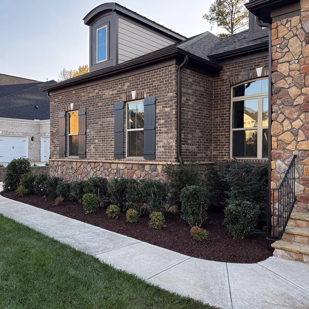 Fresh Mulch Installation for a stately brick home accented with shrubs in Weddington, NC.