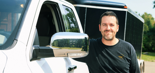 A delivery service worker standing beside a white truck, ready to transport goods efficiently.