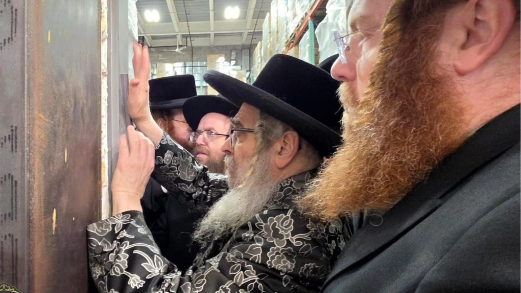 Orthodox Jewish men affixing a mezuzah to a doorway with careful attention to proper placement