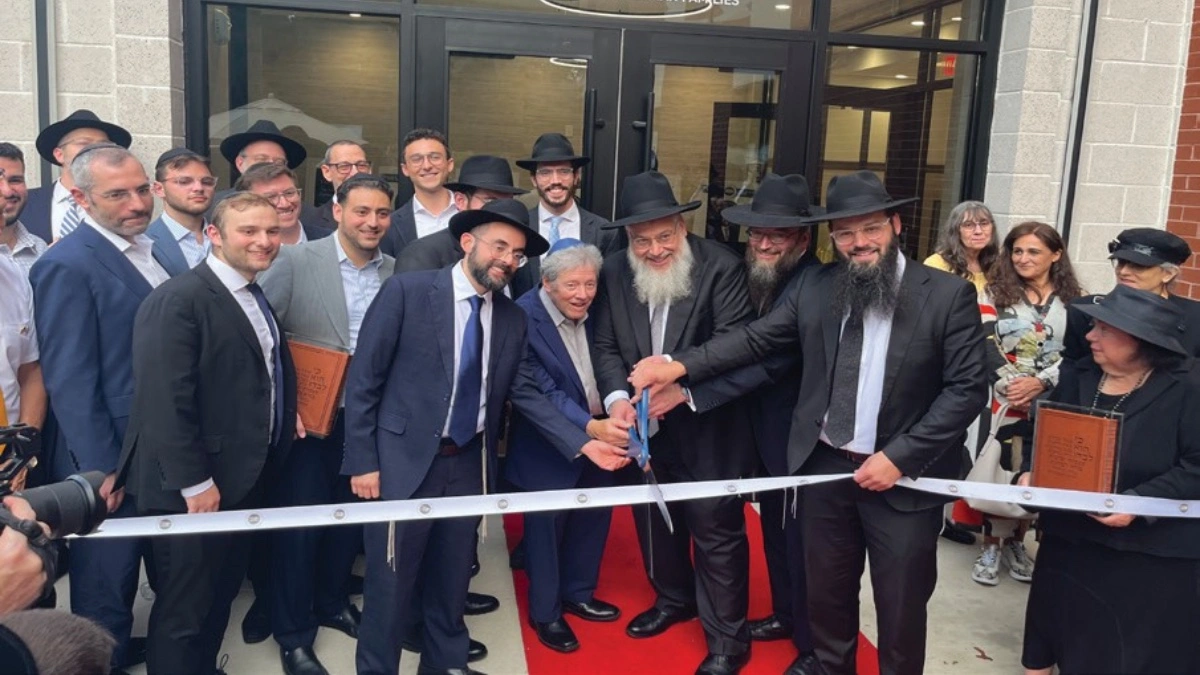 Rabbis and community leaders cutting the ribbon at the Foxman Torah Institute dedication in Cherry Hill, holding mezuzah cases as they celebrate the new building's opening