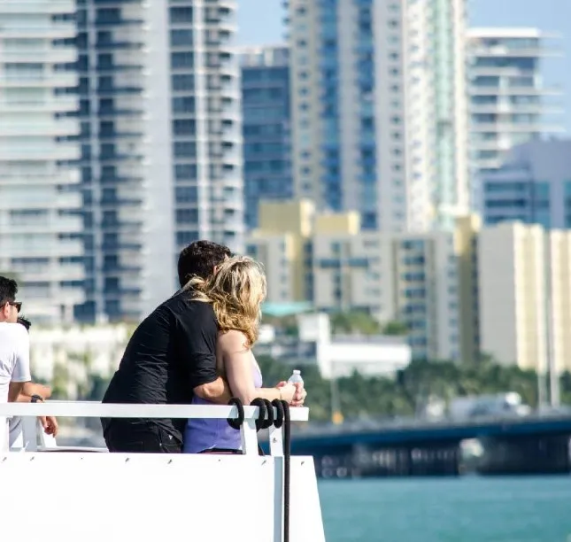 Couple embracing and looking at city buildings from a boat on the water.
