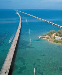 Aerial view of the Seven Mile Bridge stretching over clear blue water with a small island nearby.