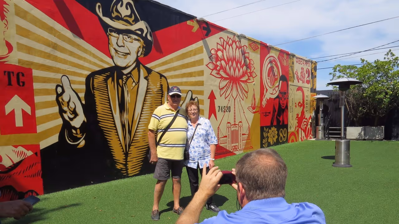 Man and women getting taking a photo near the Tony Goldman mural at the Wynwood Walls.