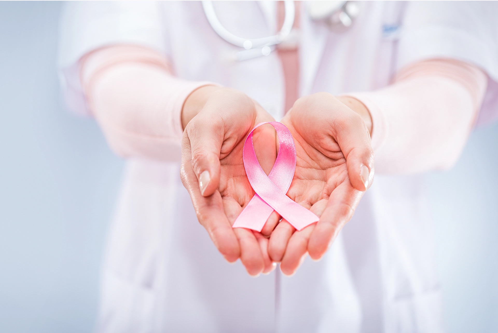 Women's hands holding a pink ribbon