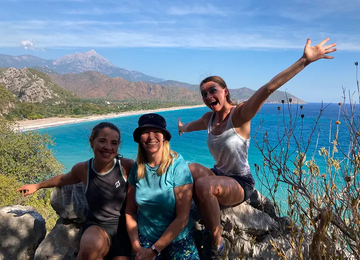 3 women on hike with sea and mountain views