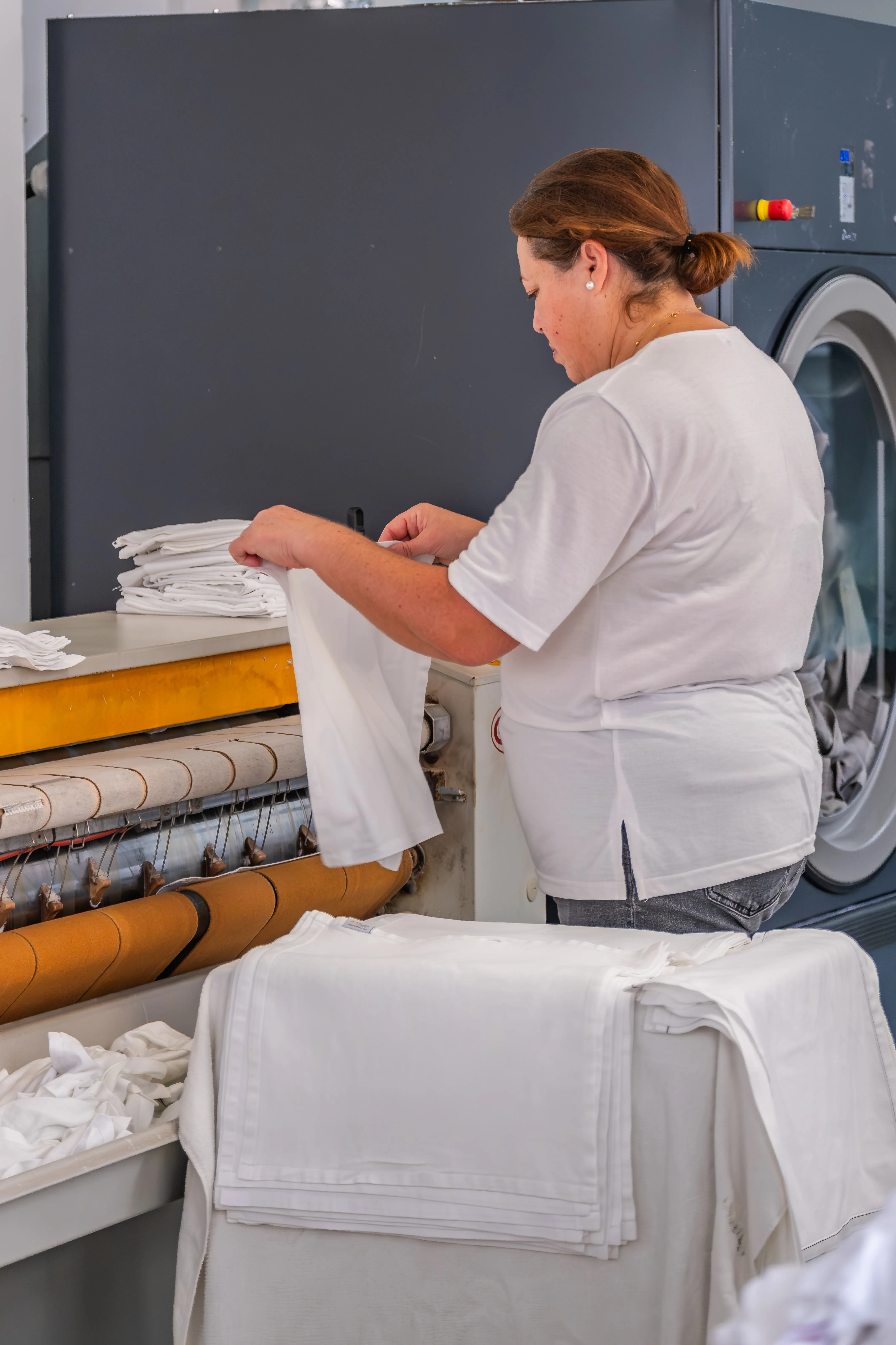 Processo de dobragem e preparação de têxteis realizado por colaboradora em lavandaria industrial.