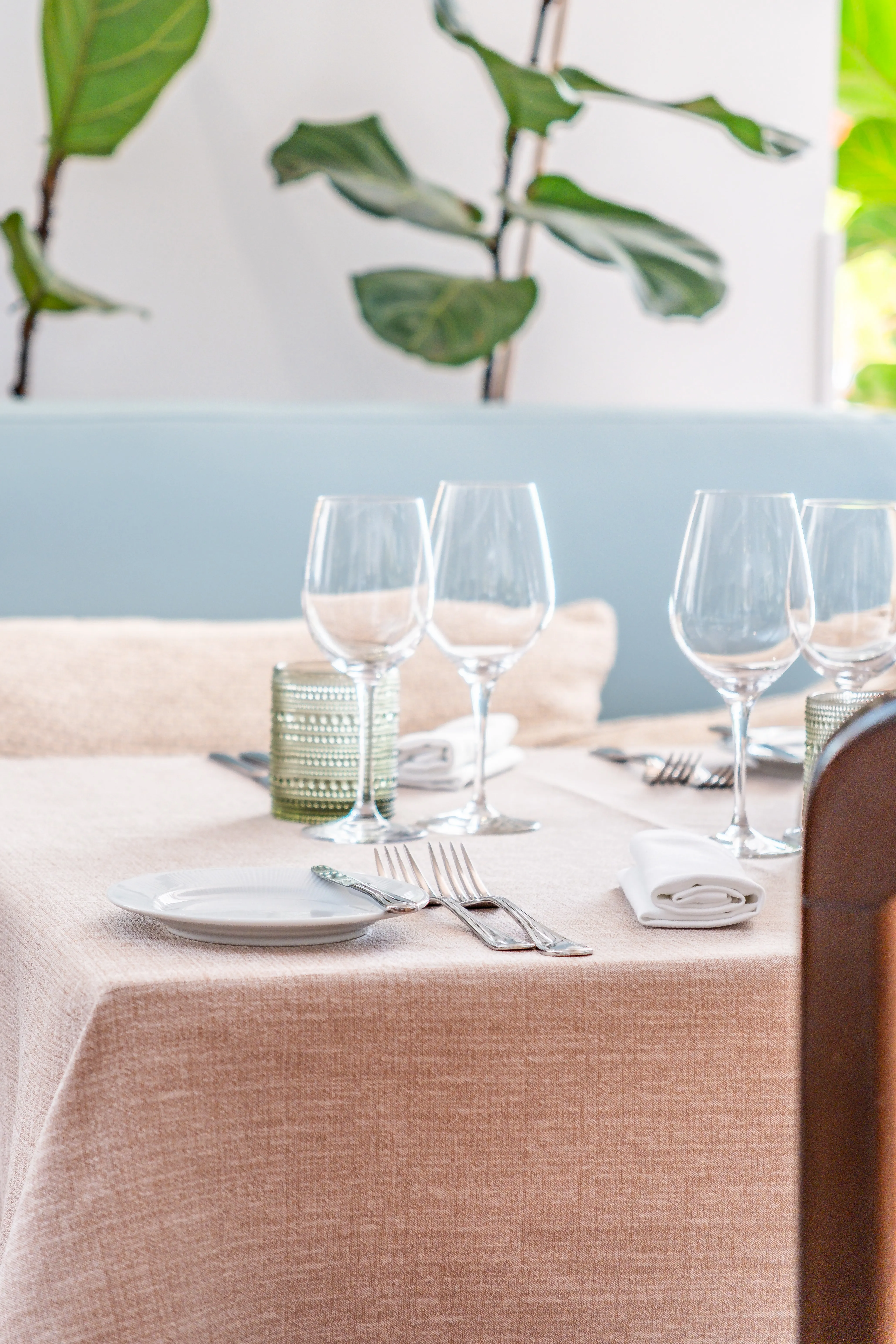 Mesa de restaurante com têxteis cuidados e mise-en-place preparada, refletindo atenção ao detalhe na restauração.