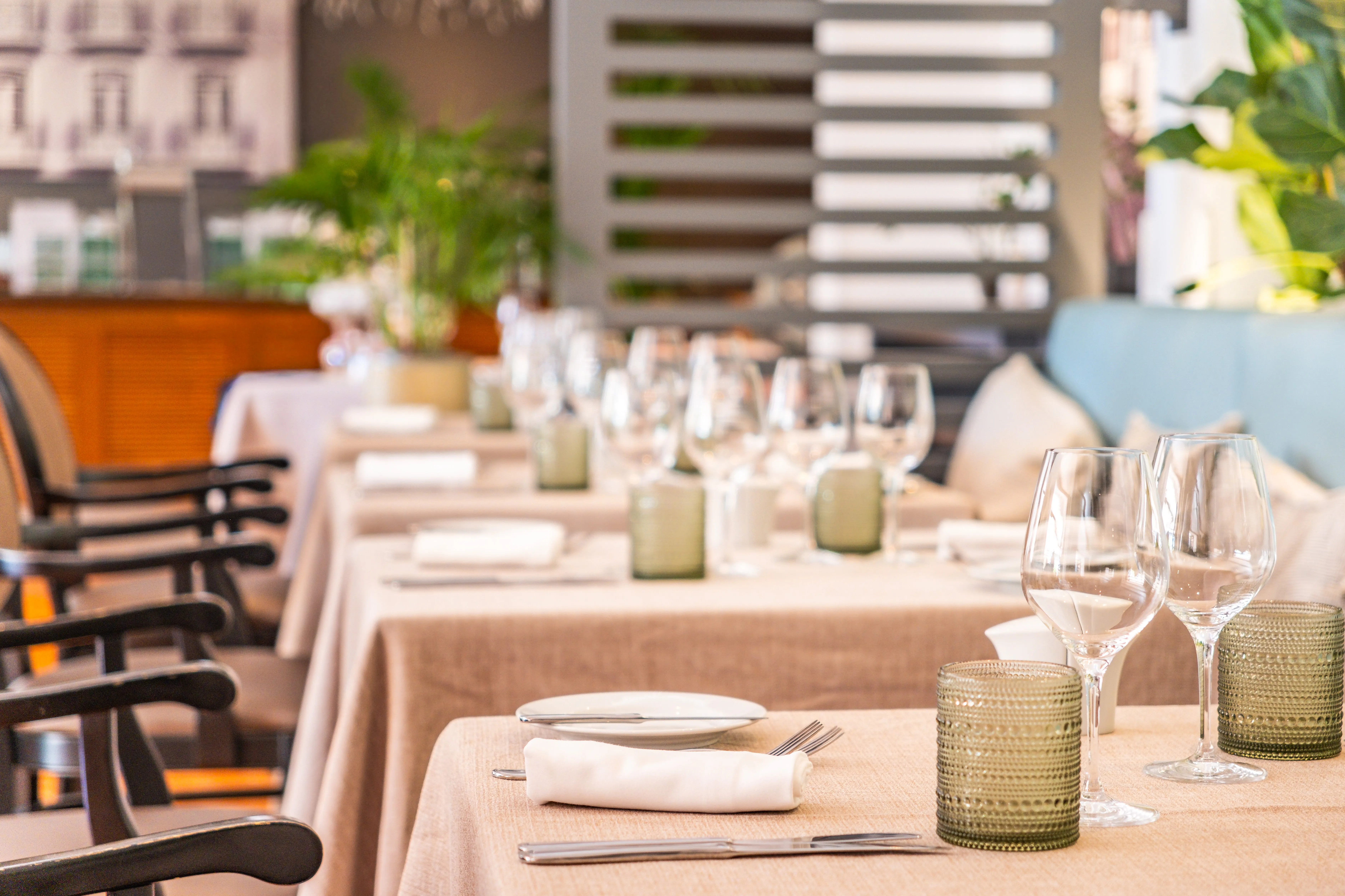 Mesas de restaurante cuidadosamente preparadas, com toalhas e guardanapos impecáveis, refletindo o cuidado têxtil no setor da restauração.