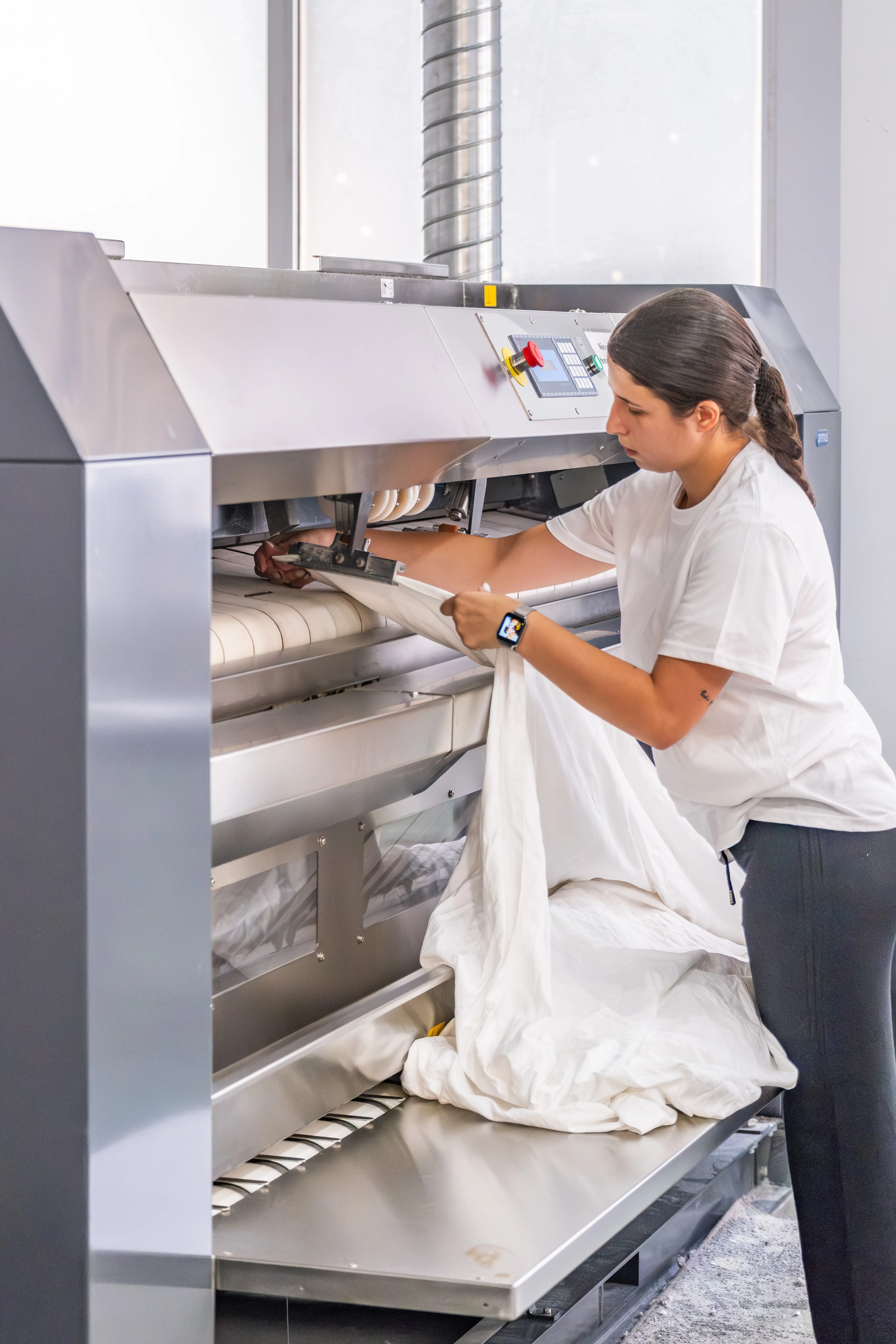 Colaboradora da Mãos à Roupa a operar equipamento industrial de tratamento e acabamento de têxteis.