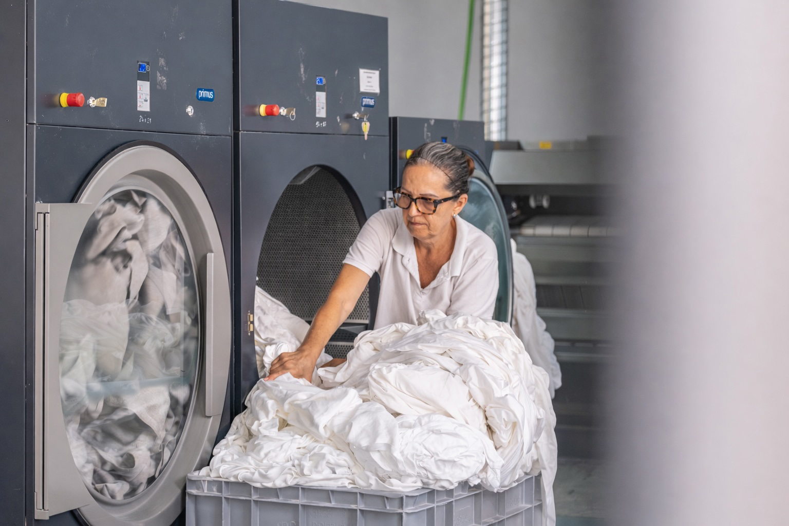 Colaboradora da Mãos à Roupa no processo de lavagem e manuseamento de têxteis em ambiente industrial.