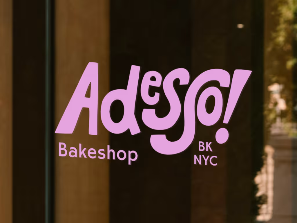 Glass window decal with purple text reading 'Adesso! Bakeshop BK NYC'.