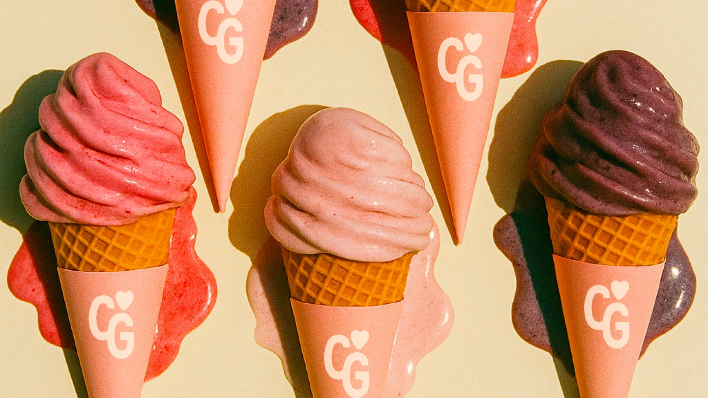 Five soft-serve ice cream cones in waffle cones with pink wrappers featuring a white CG logo and heart, arranged on a pale background with melting pink, red, and purple ice cream puddles beneath them.