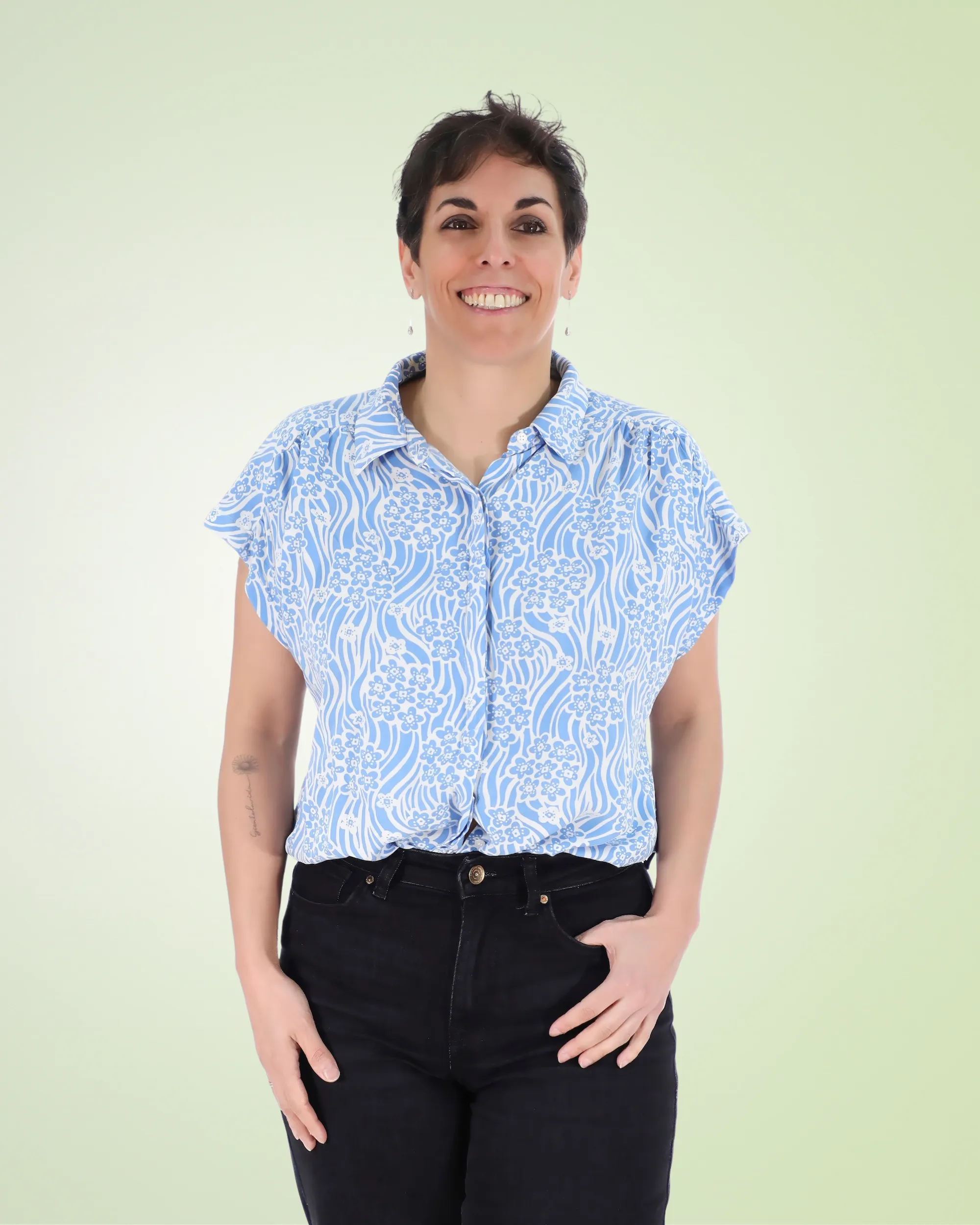 Sandra Tirado, coach de alimentación emocional, sonríe de pie sobre un fondo verde claro