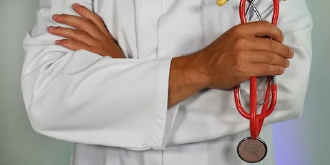A doctor holding a stethoscope with their arms crossed