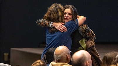 Two women embracing each other warmly in the crowded worship center at West Valley Church.