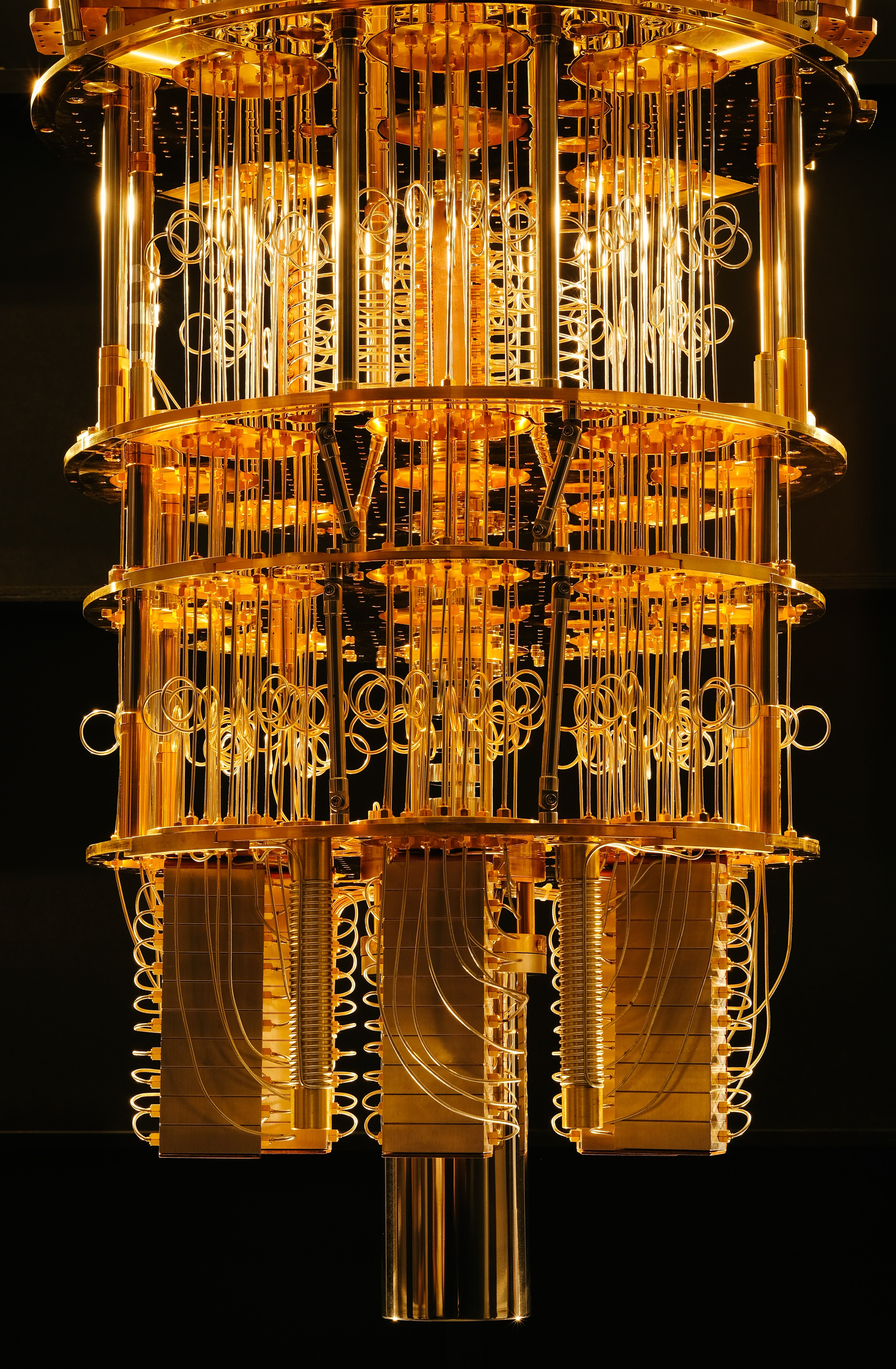 A gold-coloured quantum computer processor with multiple circular and coiled wires encased in a metallic frame.