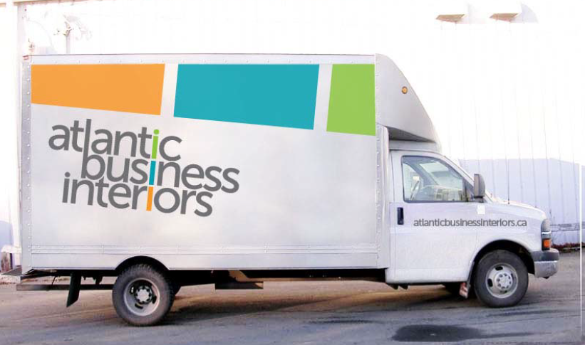 White delivery truck with Atlantic Business Interiors logo and three colored rectangles in orange, teal, and green on the side.