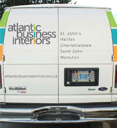 Rear view of a white van with Atlantic Business Interiors logo, a list of cities including St. John's and Halifax, and a Nova Scotia license plate.
