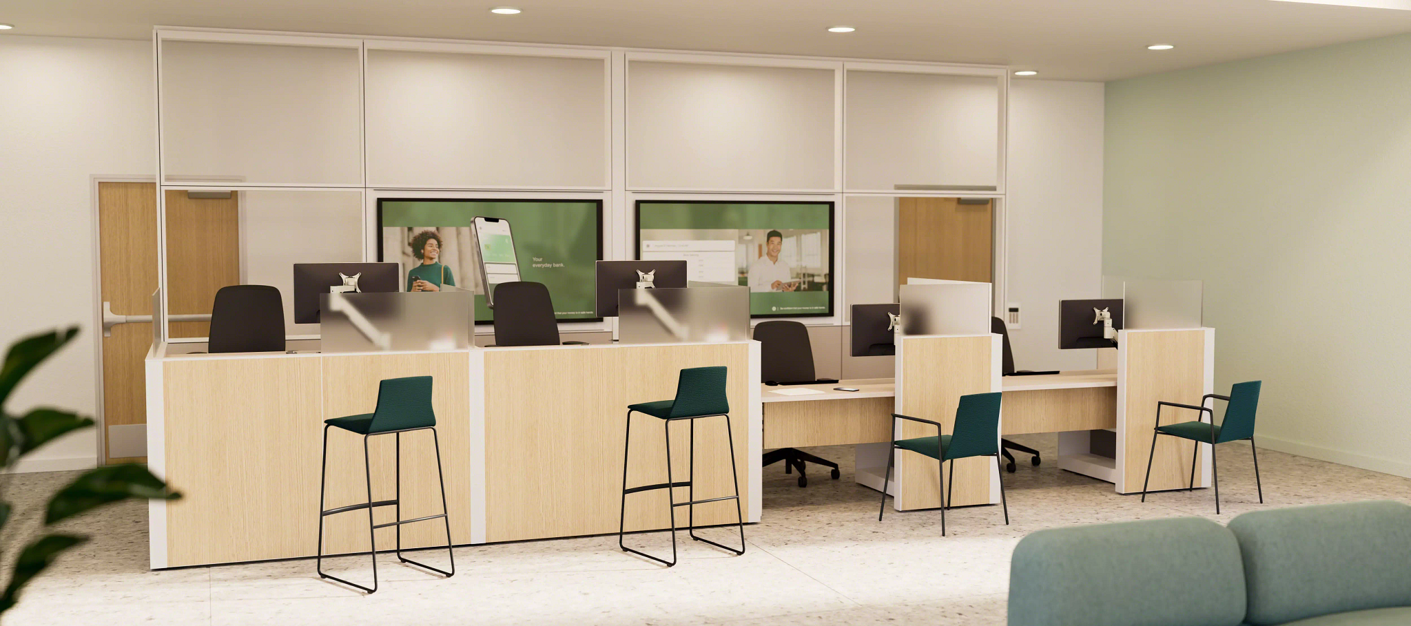 Modern bank teller area with wooden counters, green guest chairs, and computer monitors behind plexiglass dividers.