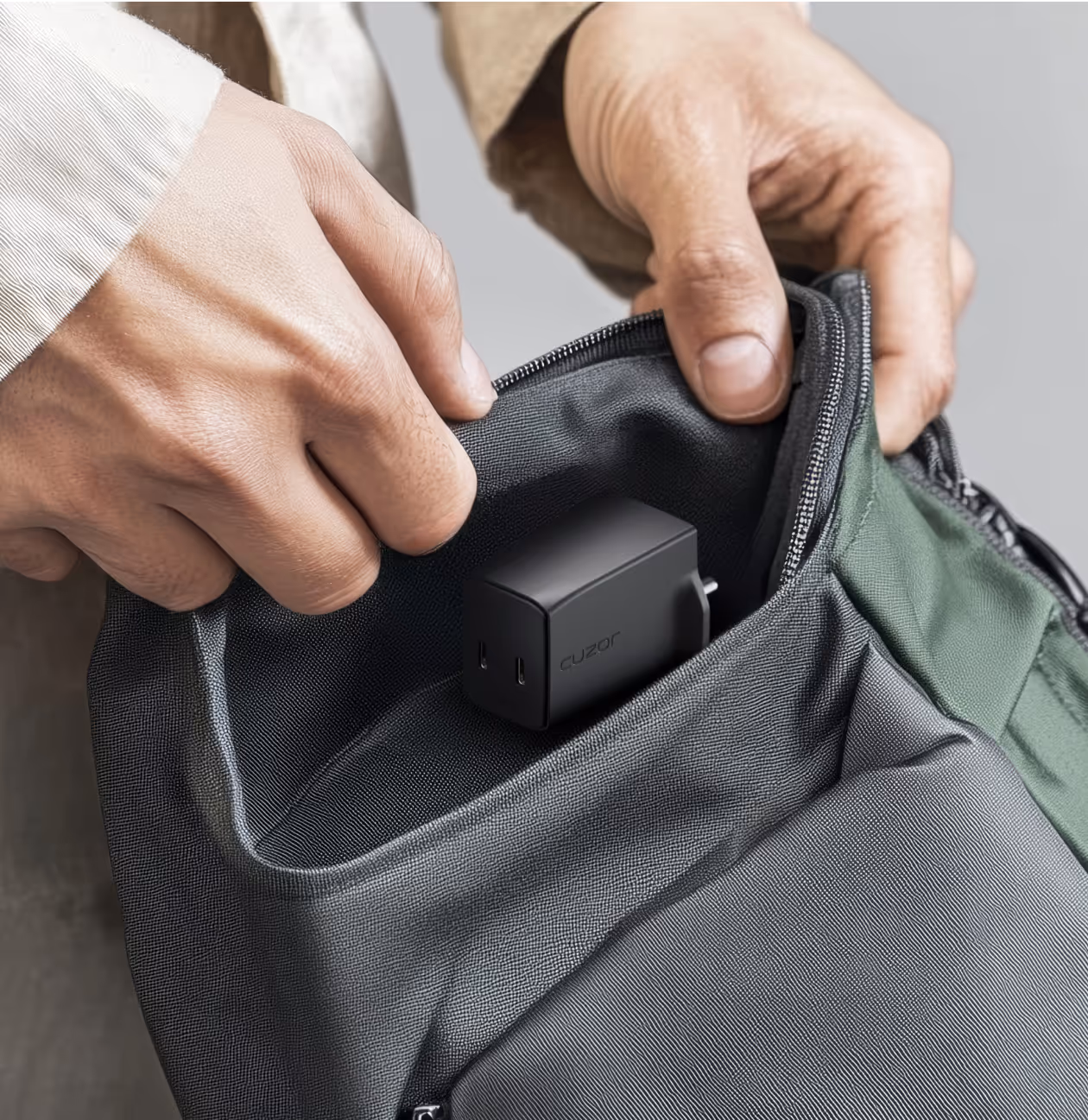 A hand retrieving a cuzor charger from a backpack.
